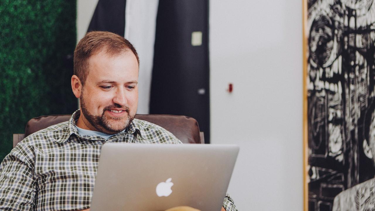 A man smiling at his laptop