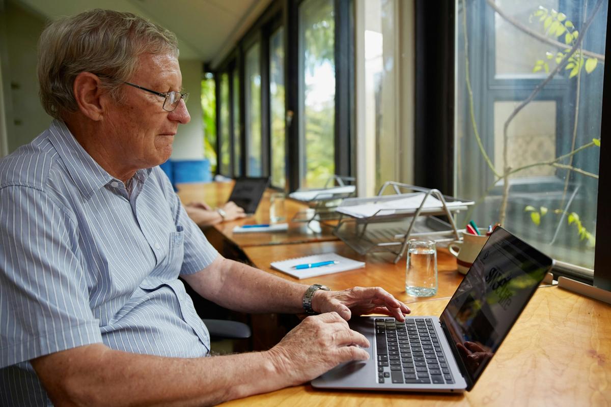 An older man working on his laptop