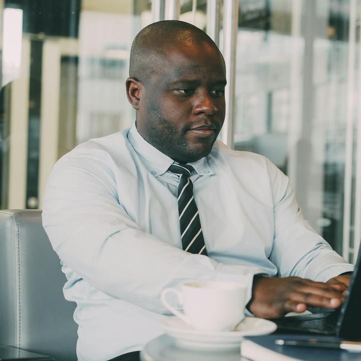 A man in a shirt and tie working on his laptop