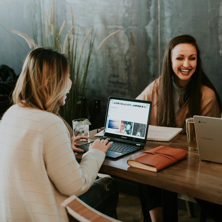 Three adults laughing together at their laptops